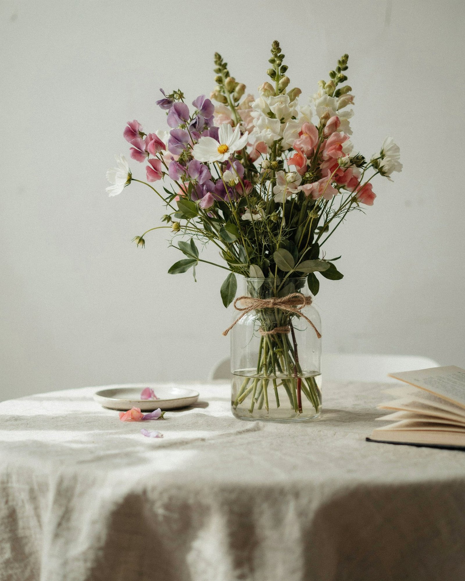 Hand-tied sweet pea and cosmos bouquet in a glass vase on linen