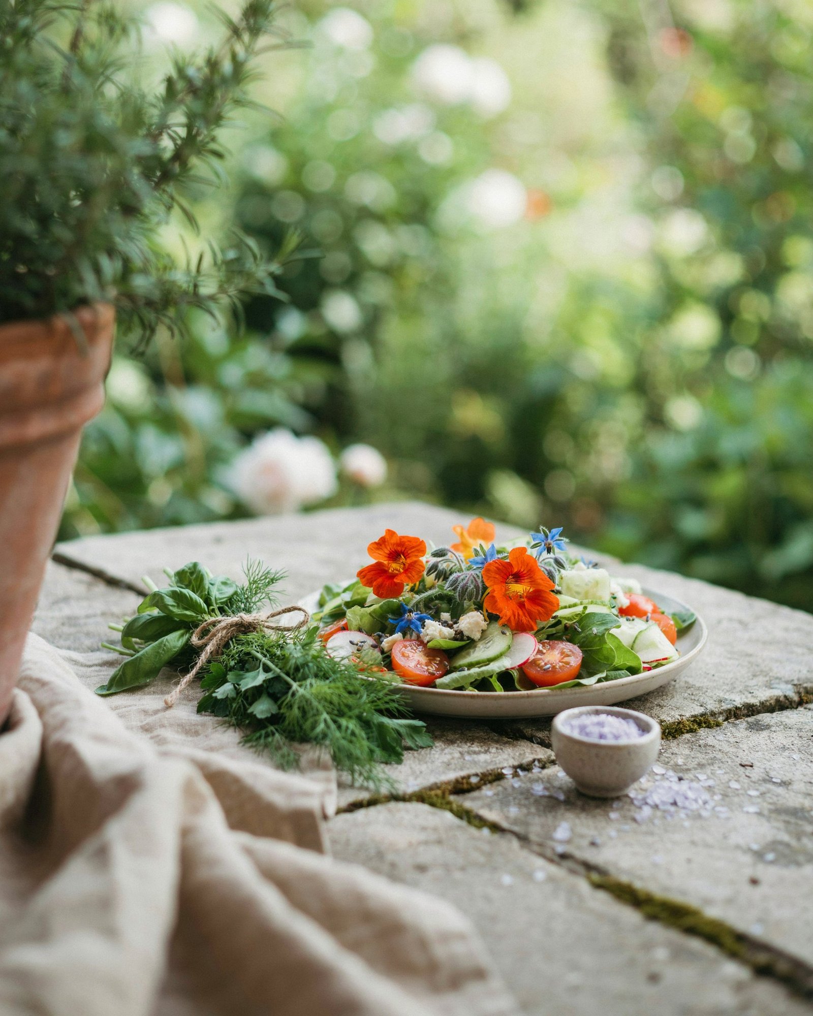 Summer salad with edible nasturtium and borage flowers on a stone table